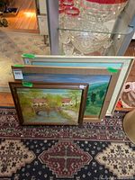 Three framed paintings leaning together showing relative sizes and frames