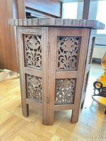 Three-quarter view showing carved panels and hinged legs