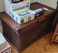 Front view of brown rattan wicker storage trunk with items on lid