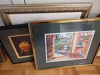 Framed Lynette Yu print, orange rose print, and ornate frame leaning together