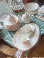 Group view of stacked plates, teapot, sugar bowl, serving pieces