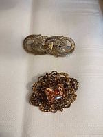 Two brooches: filigree amber stone brooch and scroll bar pin