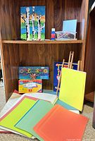 Overall lot showing easel, construction paper, Rainbow Loom kit, painting, crayons and other supplies