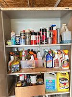 Cabinet interior showing three shelves filled with various automotive fluids
