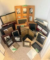 Group of assorted frames stacked against wall