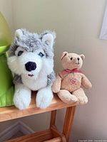 Grey and white husky plush and tan teddy bear plush sitting on shelf