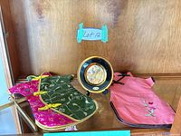 Overall lot: two dress-shaped wine bottle covers and decorative plate on stand