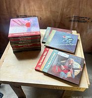 Stack of approx. twelve volumes plus three separate hardcover books from the same series on table