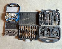 Overview of five open tool cases with drill bits, hole saws, socket set
