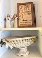 Two Willow Tree figurines beside framed quote plaque on shelf