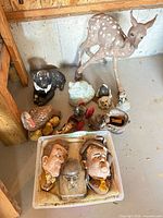Group view of all lawn ornaments, plaques in plastic bin and bust