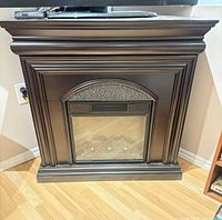 Front view of dark wood electric fireplace showing mantel and glass firebox
