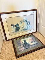 Both framed dog prints leaning against wall