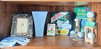 overview of shelf contents: frame, gloves, vase, books, cards, ornament, stand with golf balls