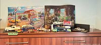 Overall view showing puzzles and multiple diecast vehicles on cabinet
