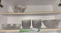 Cabinet view showing clear bowl with red pattern, six small bowls, frosted scalloped bowl, and clear low bowl