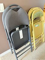 Stacked two grey folding chairs and four yellow folding chairs