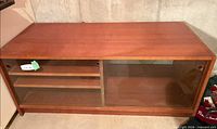 front view of wood cabinet showing two sliding glass doors, shelves interior