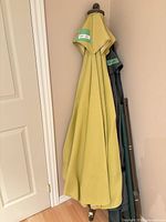 Two folded umbrellas leaning against wall, showing fabric colors and poles