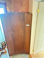 Front view of wooden wardrobe showing single door and circular pull