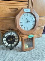 Both wall clocks upright for scale and comparison