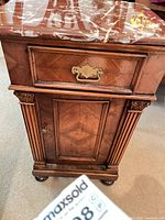 Front view showing drawer, cabinet door, marble top, fluted columns, bun feet