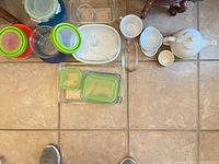 Overview of all glass containers, bakeware, and white ceramic pieces arranged on tile floor
