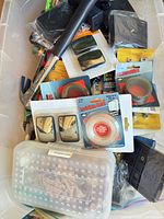 Overview of tote showing hammer, packaged mirrors, picture wire, strap, small parts box