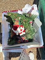 Top view of storage tote showing Santa figure, faux greenery, ribbon, ornaments