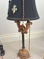 Full view of lamp showing base, column, shade, tassel and applique