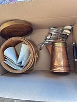 Box containing copper teapot, wooden firkin with lid, and stack of spoons