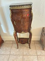 Front view of bombe-shape etagere showing veneer, ormolu mounts, door and marble top
