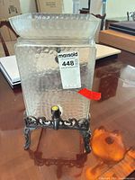 Front view of hammered glass dispenser on metal stand showing spigot and size reference