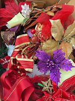 Box showing assorted red, gold, purple holiday ribbons, poinsettia picks and berry ornaments