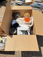 Box containing coffee grinder, carafe, towels, plastic jug and small appliance parts