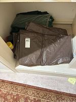 Folded brown tarp with manufacturer label showing size 6 × 8 ft; green tarp folded underneath