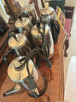 Group of five stainless electric percolators on wooden table