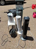 Group of five fans: three tower fans (one boxed), one white compact digital fan, one black desk fan