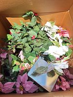 Box of mixed artificial holiday stems including pink poinsettias, white poinsettias, holly and ivy