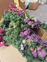 Two decorated evergreen pieces with purple ornaments and ribbons