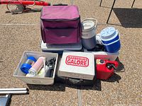 Group shot of all coolers, jugs, fuel can, grill cover and accessory bins