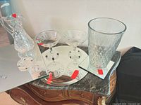 All items grouped on dresser: cut crystal pitcher, two etched coupes on round mirrored tray, pressed glass vase on mirror tile, additional mirror tiles visible