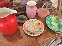 Group view of pitcher, vase, glass basket, floral bowl, leaf plate on wooden surface