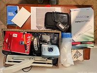 Full lot overview on tabletop showing cameras, router, battery box, lamp arm, SD card, office supplies