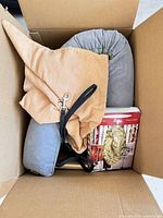 Grey pillow, tan purse, red game, partial book