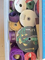 Top view of bin showing multiple wired ribbon spools in purple, gold and patterned designs