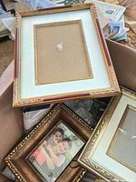 Box containing three ornate gold and bronze frames with mats