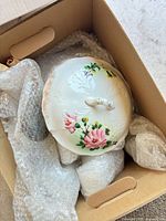 Top view of floral porcelain lid and wrapped contents in box
