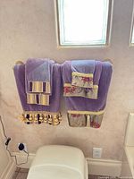 Two purple bath towels with decorative bands and tassels hanging on towel bar