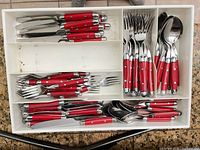 Entire flatware set in tray showing knives, forks, spoons with red handles